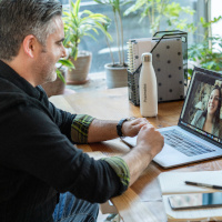 Photo of a man talking to someone via a video call on his laptop.