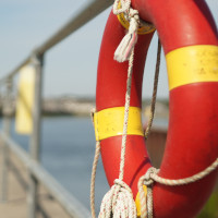 A life saving floatation device tied to the rail of a ship.